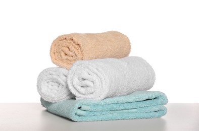 Soft colorful terry towels on light table against white background