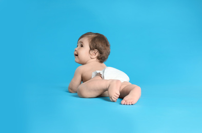 Photo of Cute little baby in diaper on light blue background