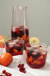 Photo of Delicious Red Sangria with fruits on white tablecloth