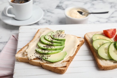 Photo of Slices of bread with different toppings on white wooden board