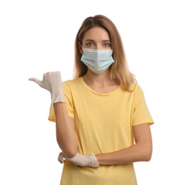 Photo of Young woman in medical gloves and protective mask pointing thumb aside on white background