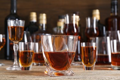 Different delicious liqueurs in glasses and bottles on wooden table