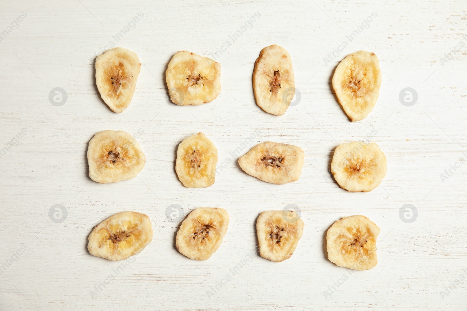 Photo of Flat lay composition with banana slices on wooden table. Dried fruit as healthy snack