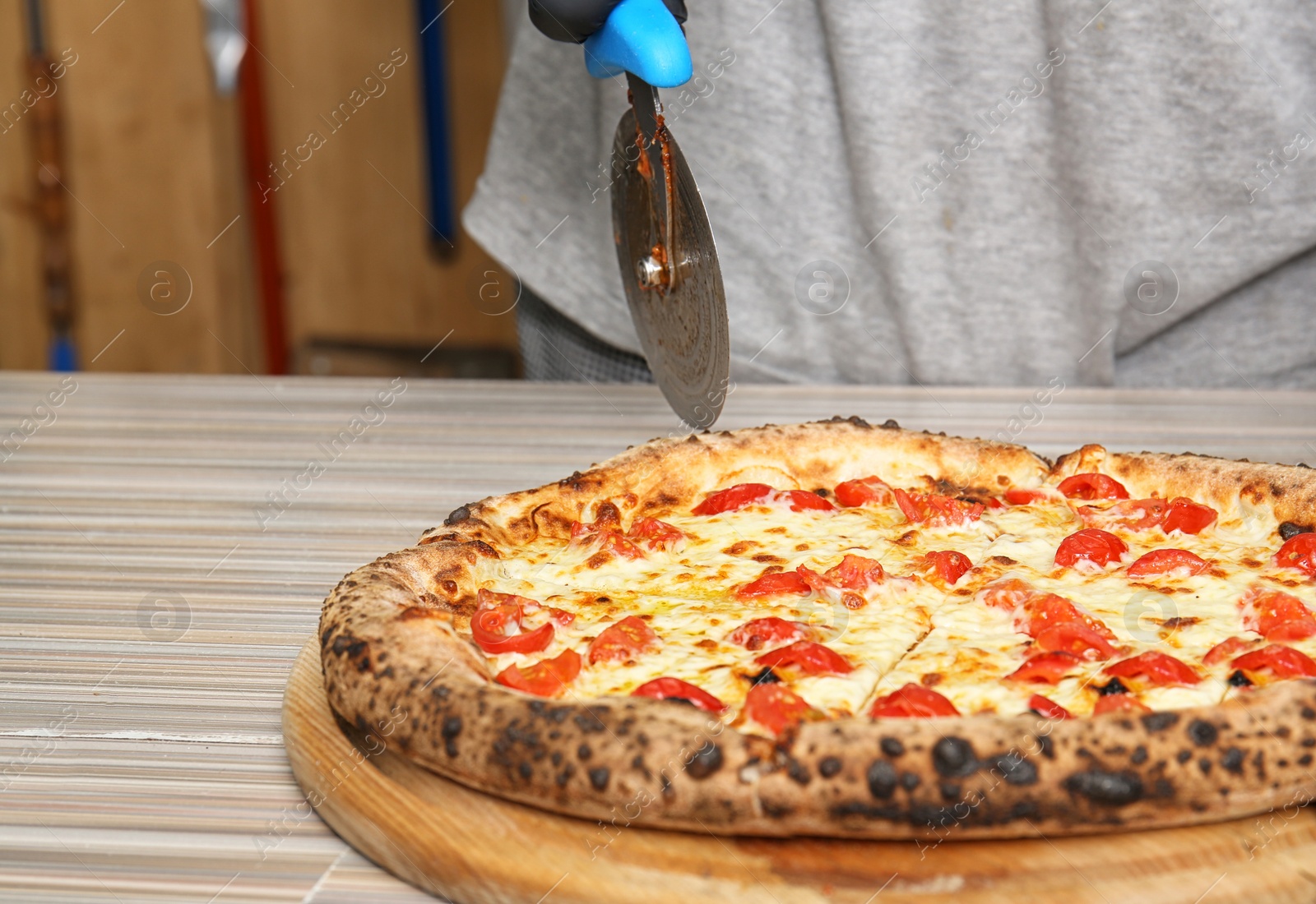 Photo of Professional chef cutting Italian oven baked pizza in restaurant, closeup