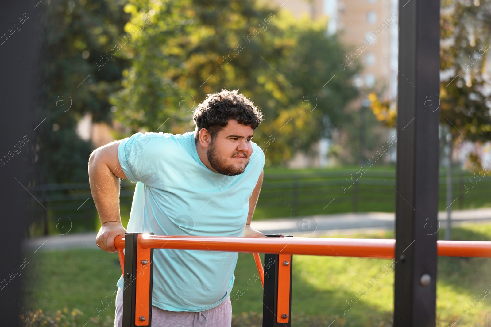 Photo of Young overweight man training on sports ground