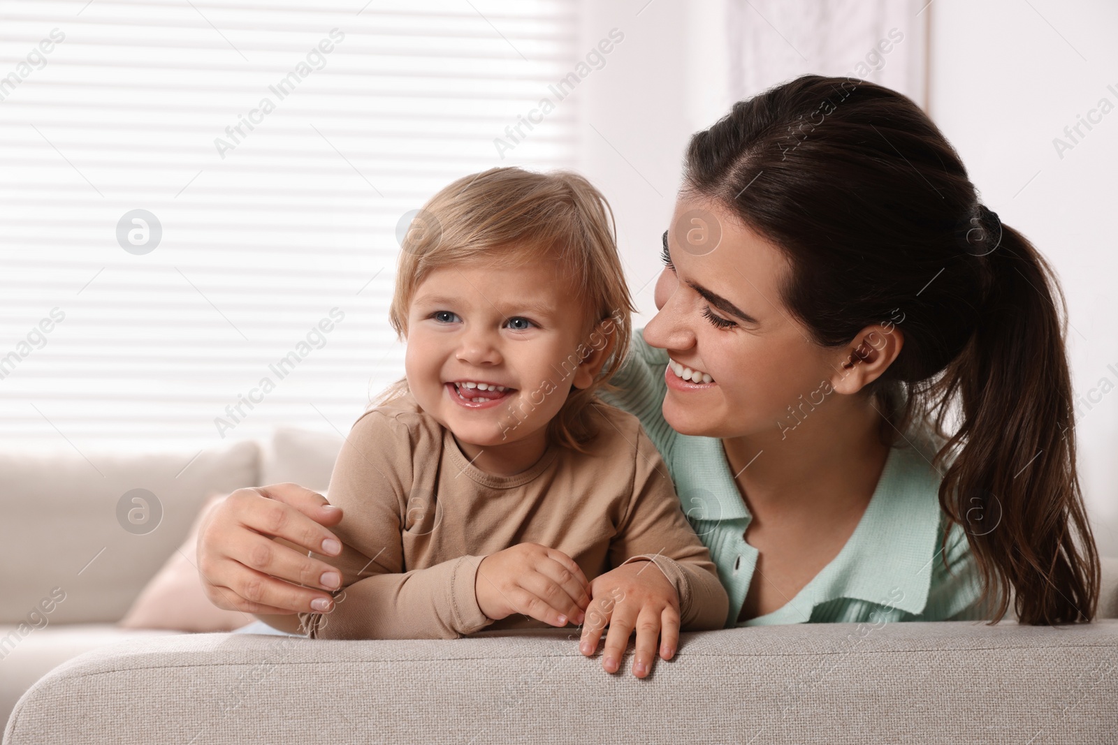 Photo of Mother with her cute little daughter on sofa at home, space for text