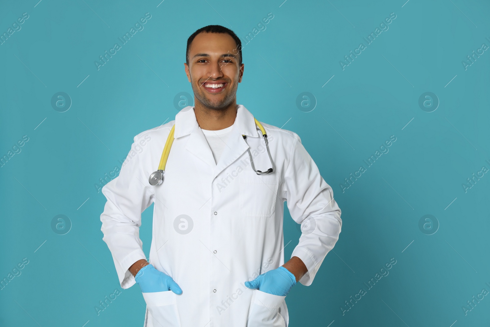 Photo of Happy doctor or medical assistant (male nurse) with stethoscope on turquoise background