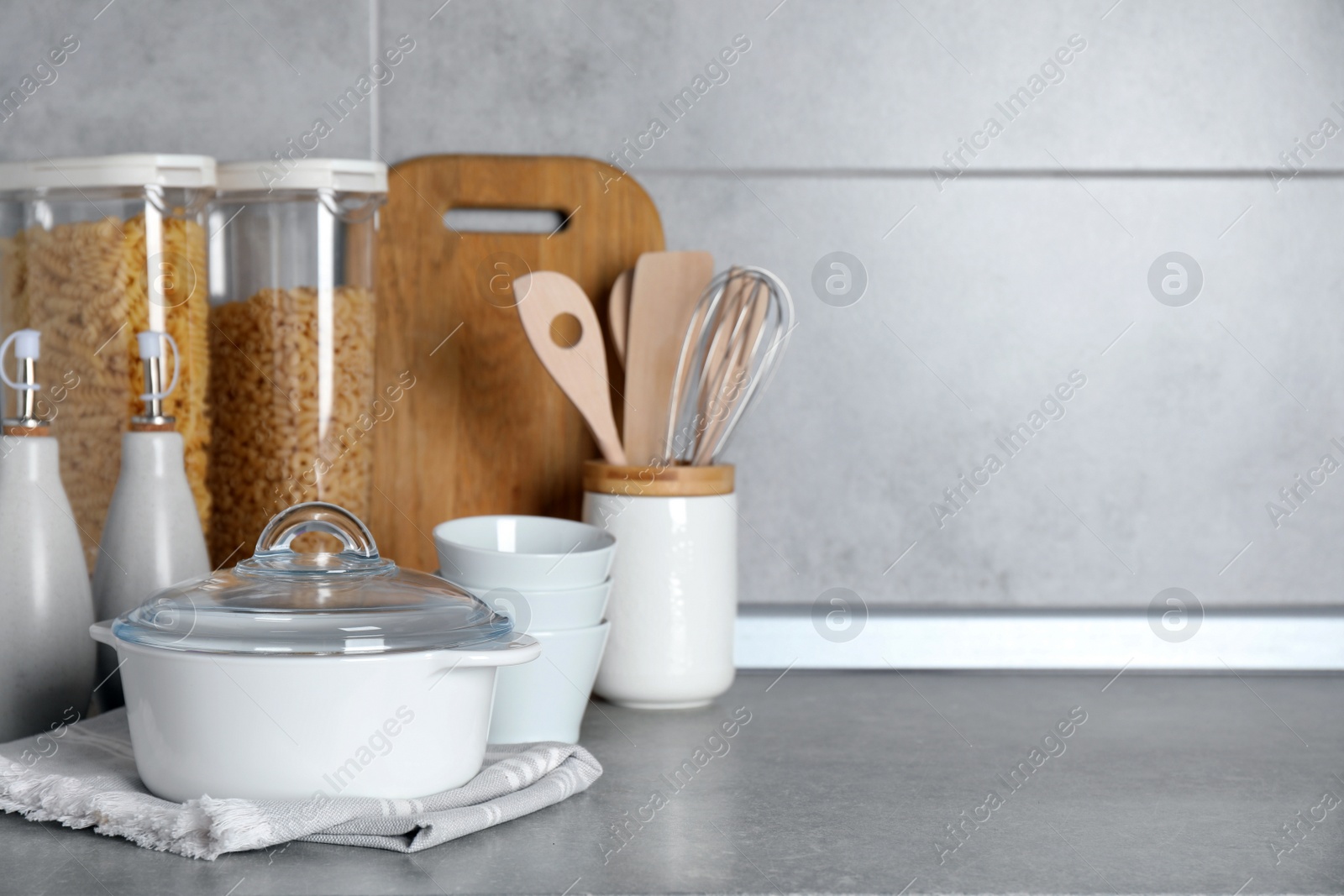 Photo of Set of different cooking utensils on grey countertop in kitchen. Space for text