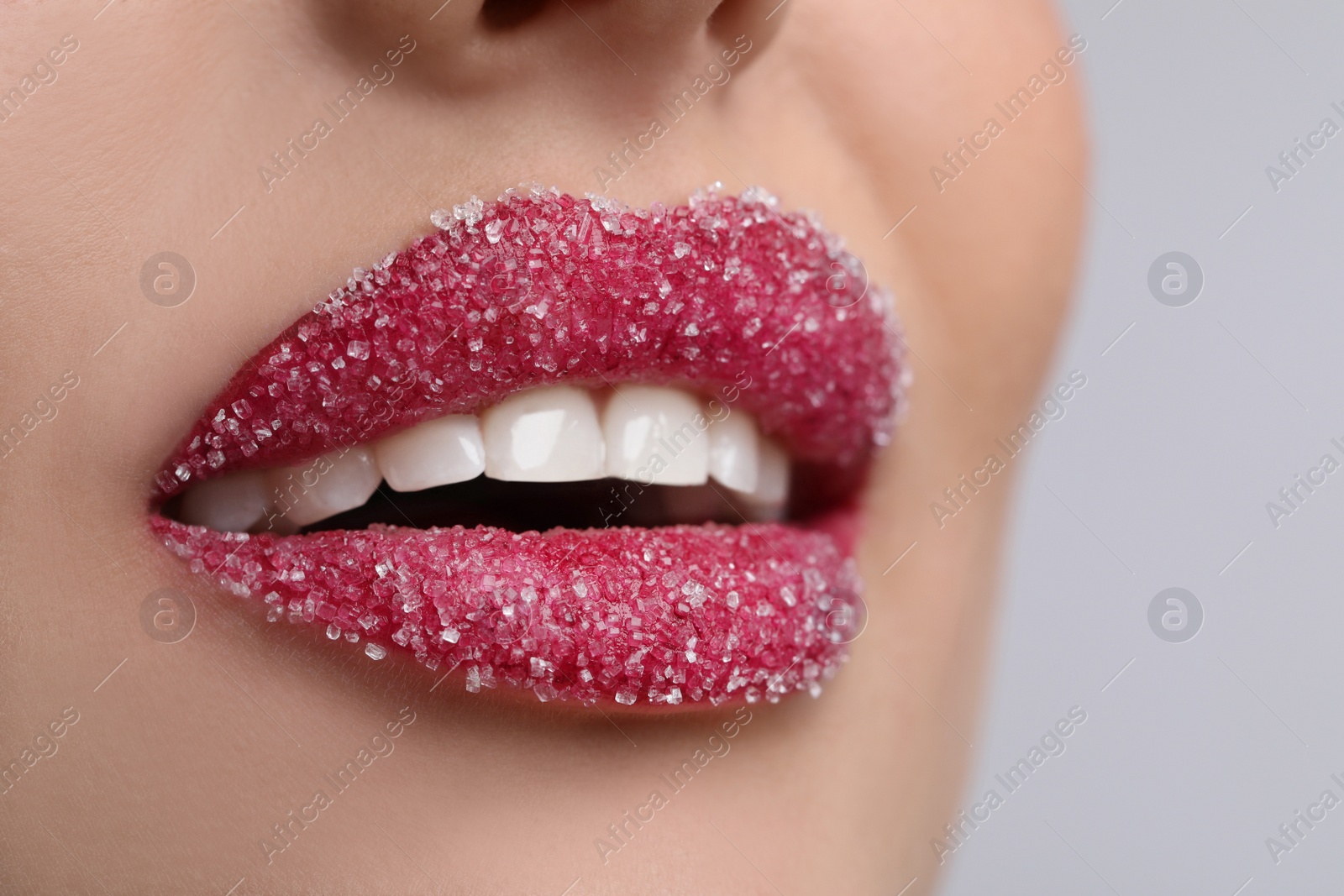 Photo of Young woman with beautiful lips covered in sugar on light background, closeup