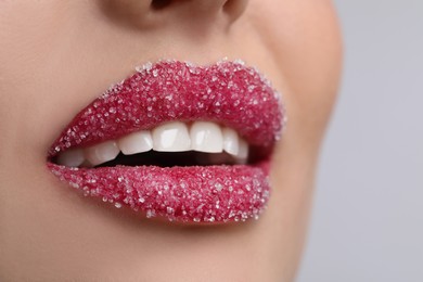 Young woman with beautiful lips covered in sugar on light background, closeup