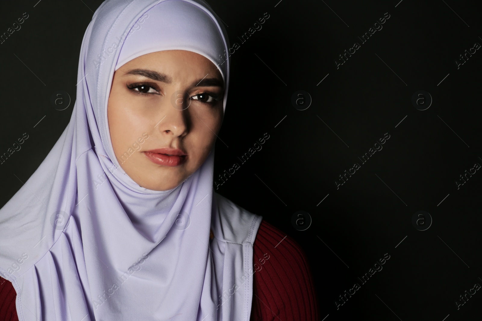 Photo of Portrait of Muslim woman in hijab on dark background. Space for text