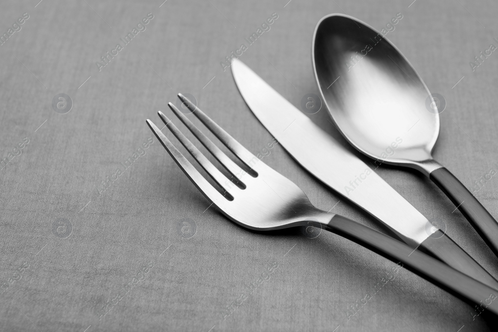 Photo of Set of shiny silver cutlery on grey table, closeup
