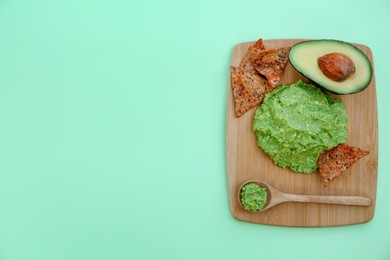 Delicious guacamole made of avocados, nachos and cut fruit on color background, top view. Space for text