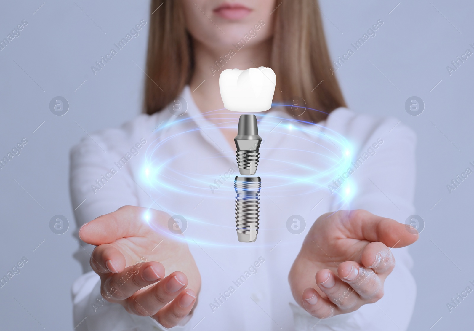Image of Woman demonstrating dental implant on light background, closeup