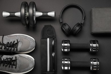 Sports equipment, headphones and sneakers on black background, flat lay