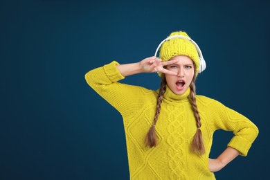 Young woman listening to music with headphones on dark blue background