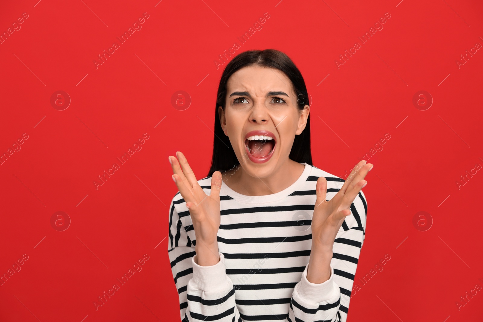 Photo of Angry young woman on red background. Hate concept