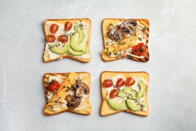 Photo of Different toasts with avocado, cherry tomatoes, mushrooms and chia seeds on grey background, top view