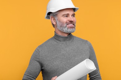 Photo of Architect in hard hat holding draft on orange background