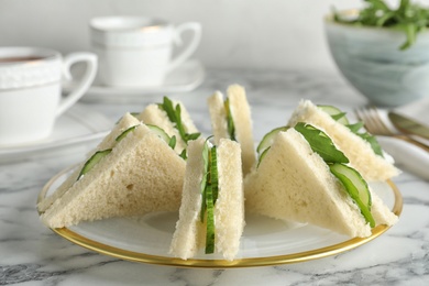 Photo of Plate with traditional English cucumber sandwiches on table