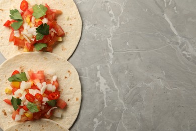 Photo of Delicious tacos with vegetables and parsley on grey marble table, top view. Space for text