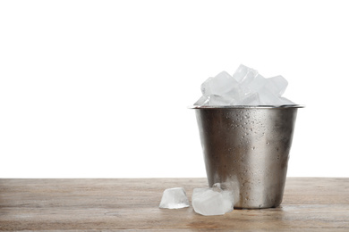 Metal bucket with ice cubes on wooden table against white background