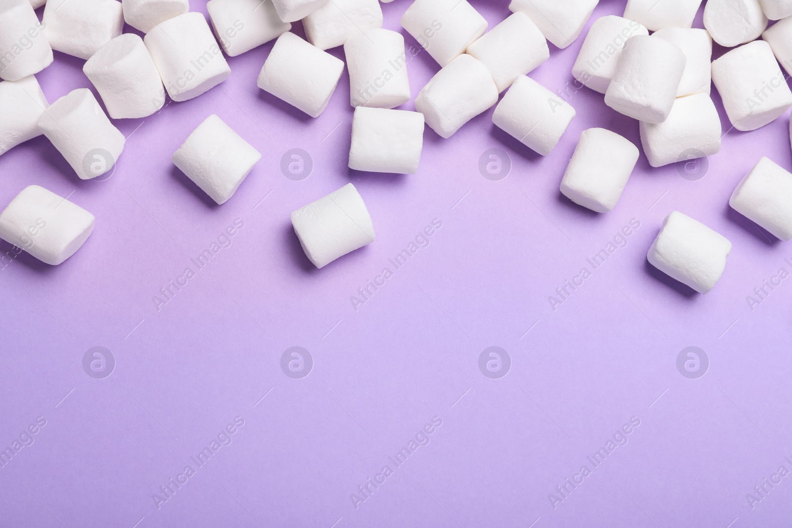 Photo of Delicious puffy marshmallows on lilac background, flat lay. Space for text