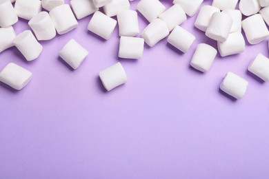 Delicious puffy marshmallows on lilac background, flat lay. Space for text