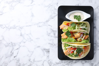 Photo of Yummy fish tacos served on white marble table, top view. Space for text