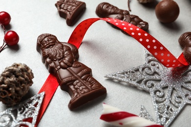 Composition with chocolate Santa Claus candies and Christmas decorations on light grey table