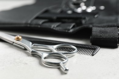 Photo of Hairdresser tools. Professional scissors, combs and leather organizer on white table, closeup