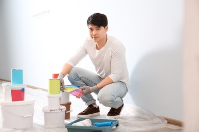 Male decorator holding color palette samples on white background