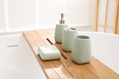 Photo of Set of bath accessories on tub in bathroom