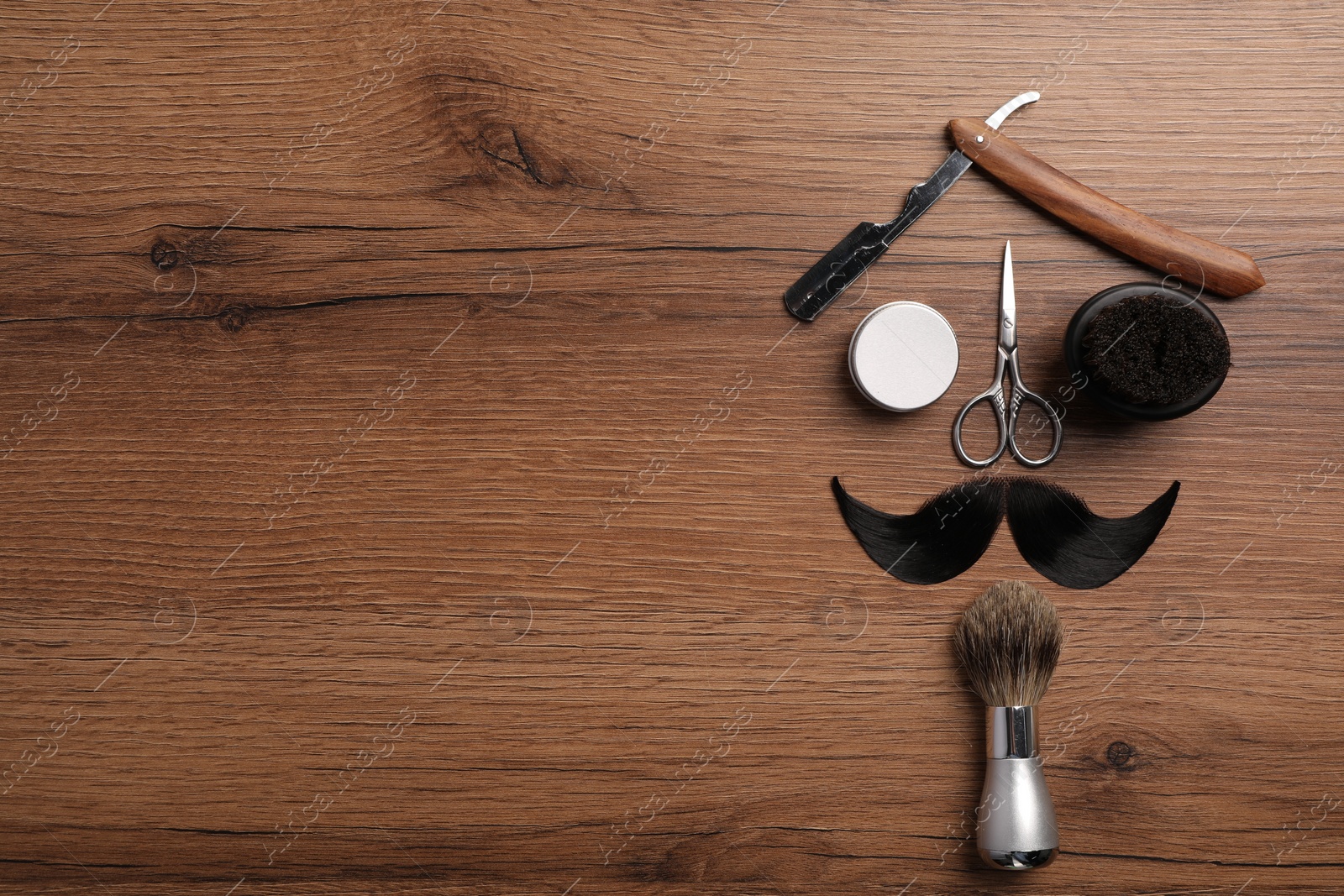 Photo of Artificial moustache and barber tools on wooden table, flat lay. Space for text