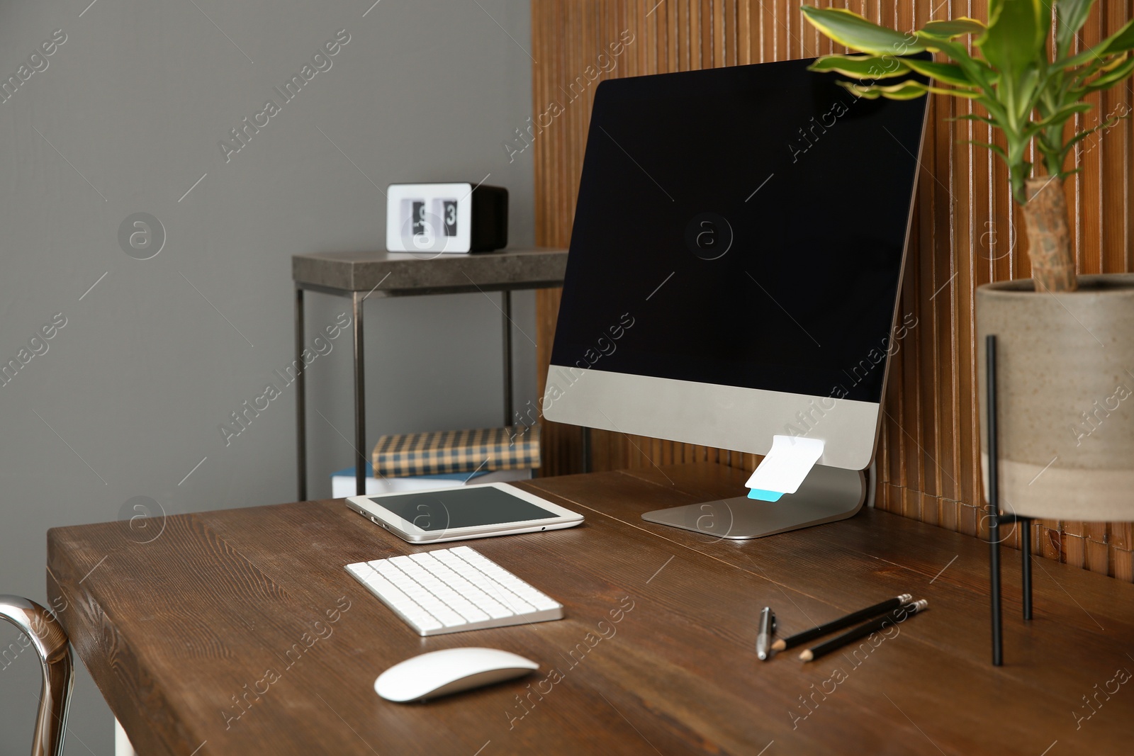 Photo of Stylish workplace with modern computer near wooden wall. Space for text