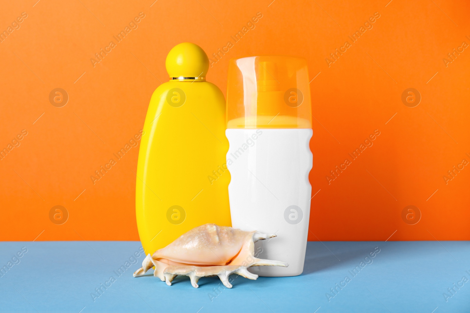 Photo of Different suntan products and seashell on color background
