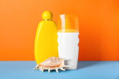 Different suntan products and seashell on color background