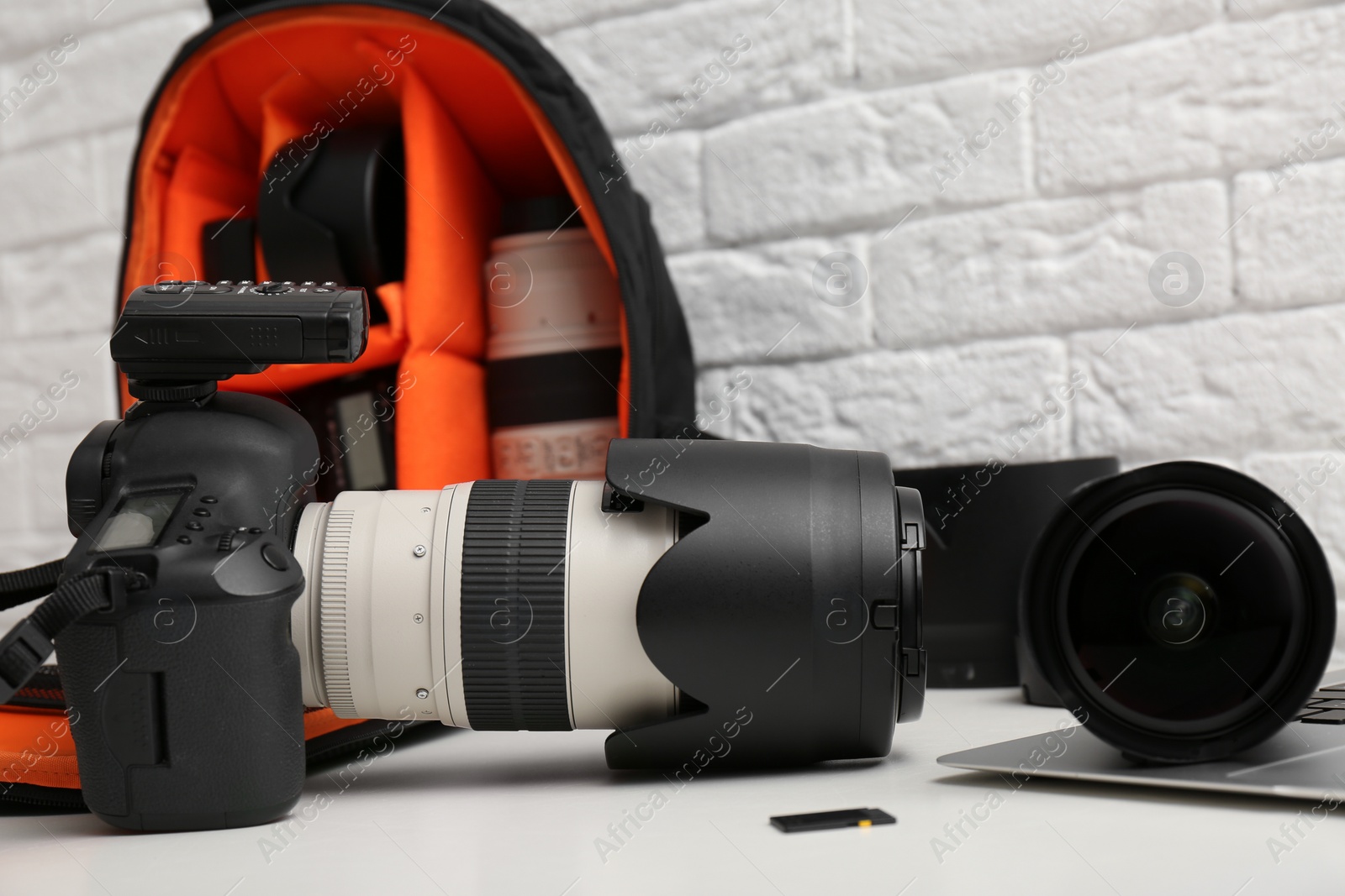 Photo of Camera and backpack with professional photographer's equipment on table indoors