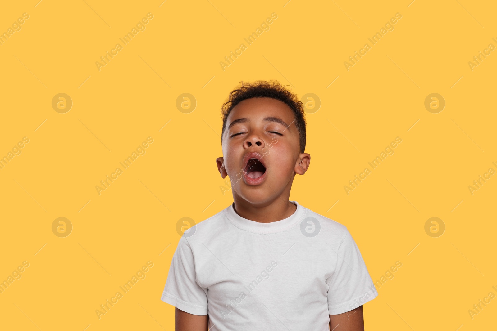 Photo of Boy yawning on yellow background. Insomnia problem
