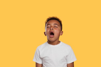 Photo of Boy yawning on yellow background. Insomnia problem