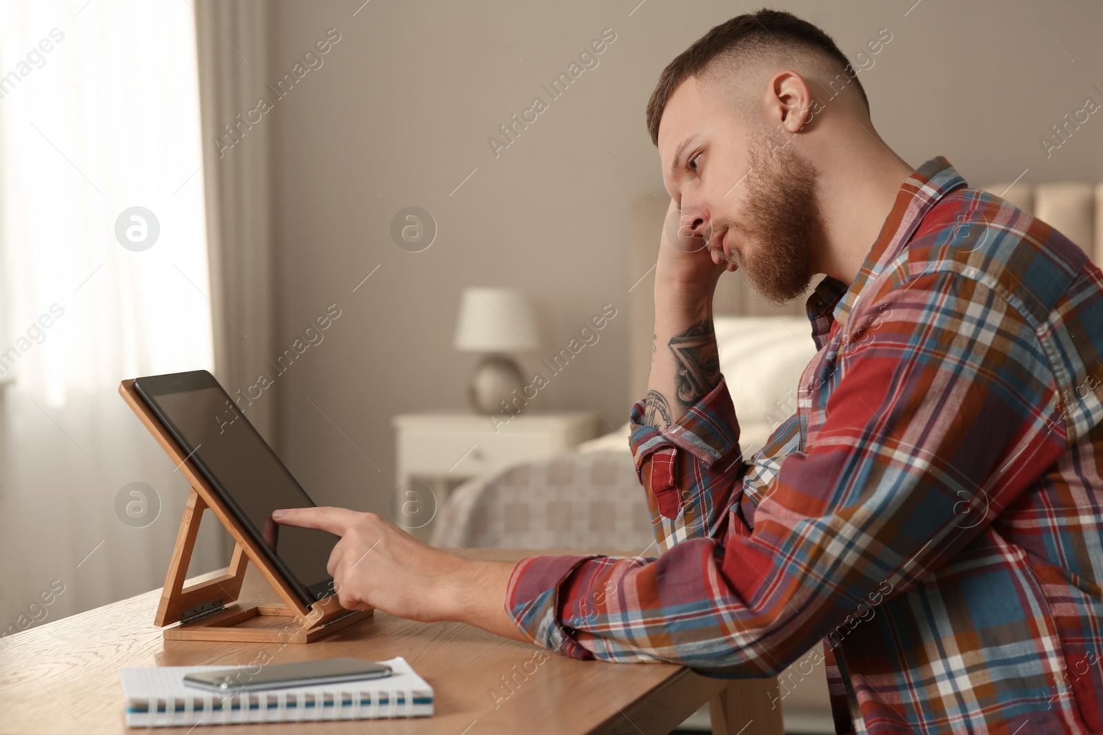 Photo of Online test. Man studying with tablet at home