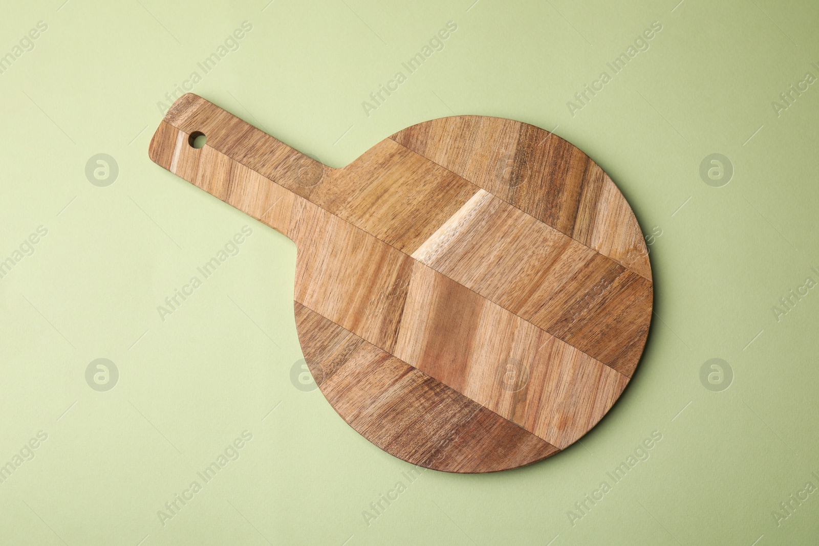 Photo of One wooden board on light olive background, top view