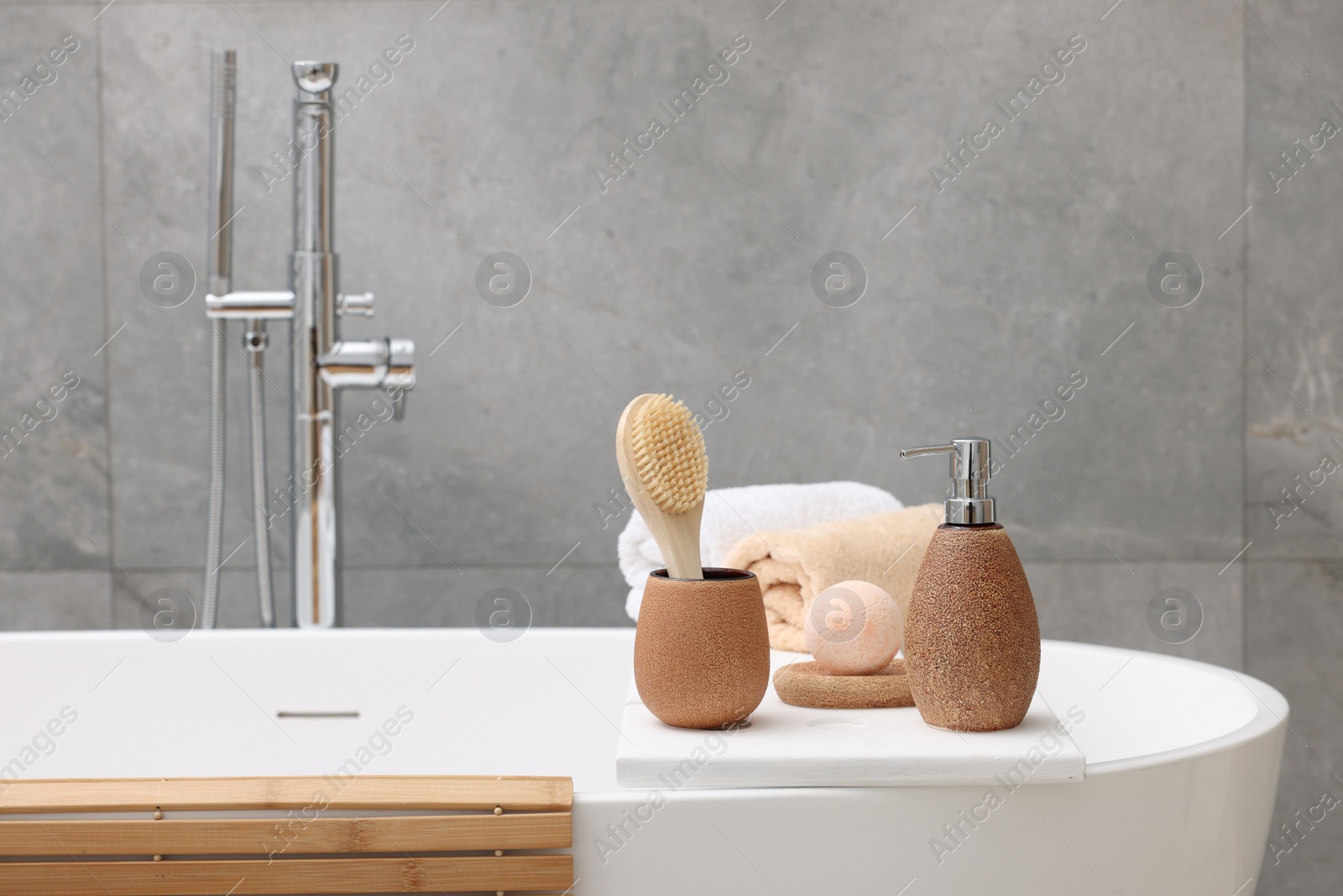 Photo of Different personal care products and accessories on bath tub in bathroom, space for text