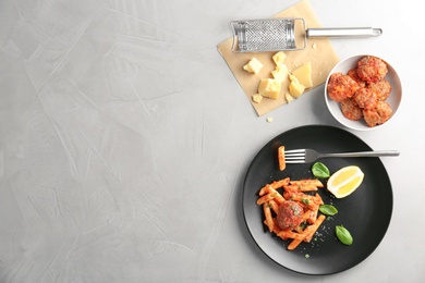 Photo of Delicious pasta with meatballs and tomato sauce on grey background