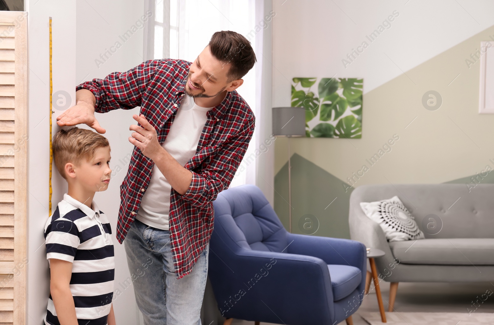 Photo of Young man measuring his son's height at home