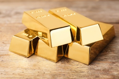 Precious shiny gold bars on wooden background