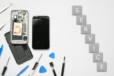 Image of Damaged smartphone and repair tool set on white background, flat lay
