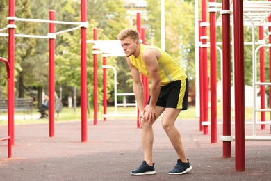 Young man suffering from knee pain on sports ground