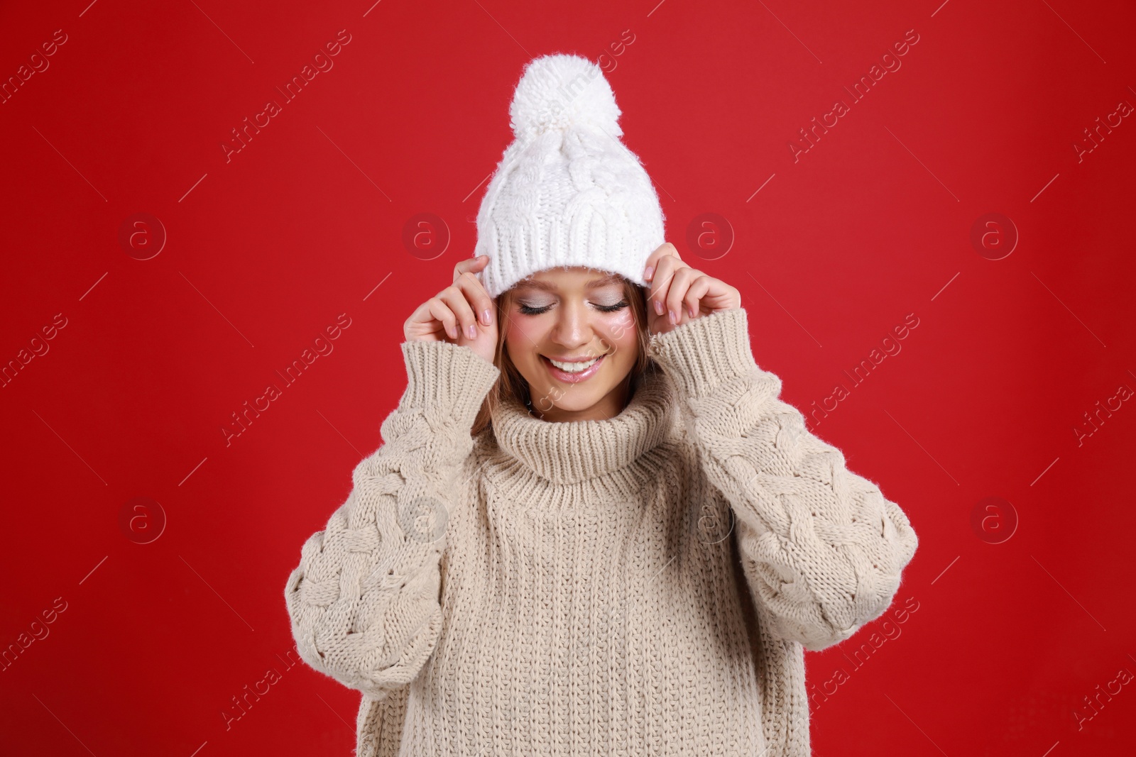 Photo of Young woman in warm sweater and hat on red background. Winter season