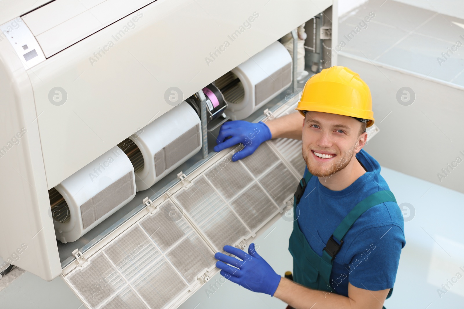 Photo of Professional technician maintaining modern air conditioner indoors